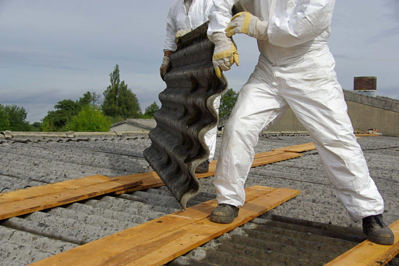 Image of two people removing a asbestos roof from a building. asbestos roofs