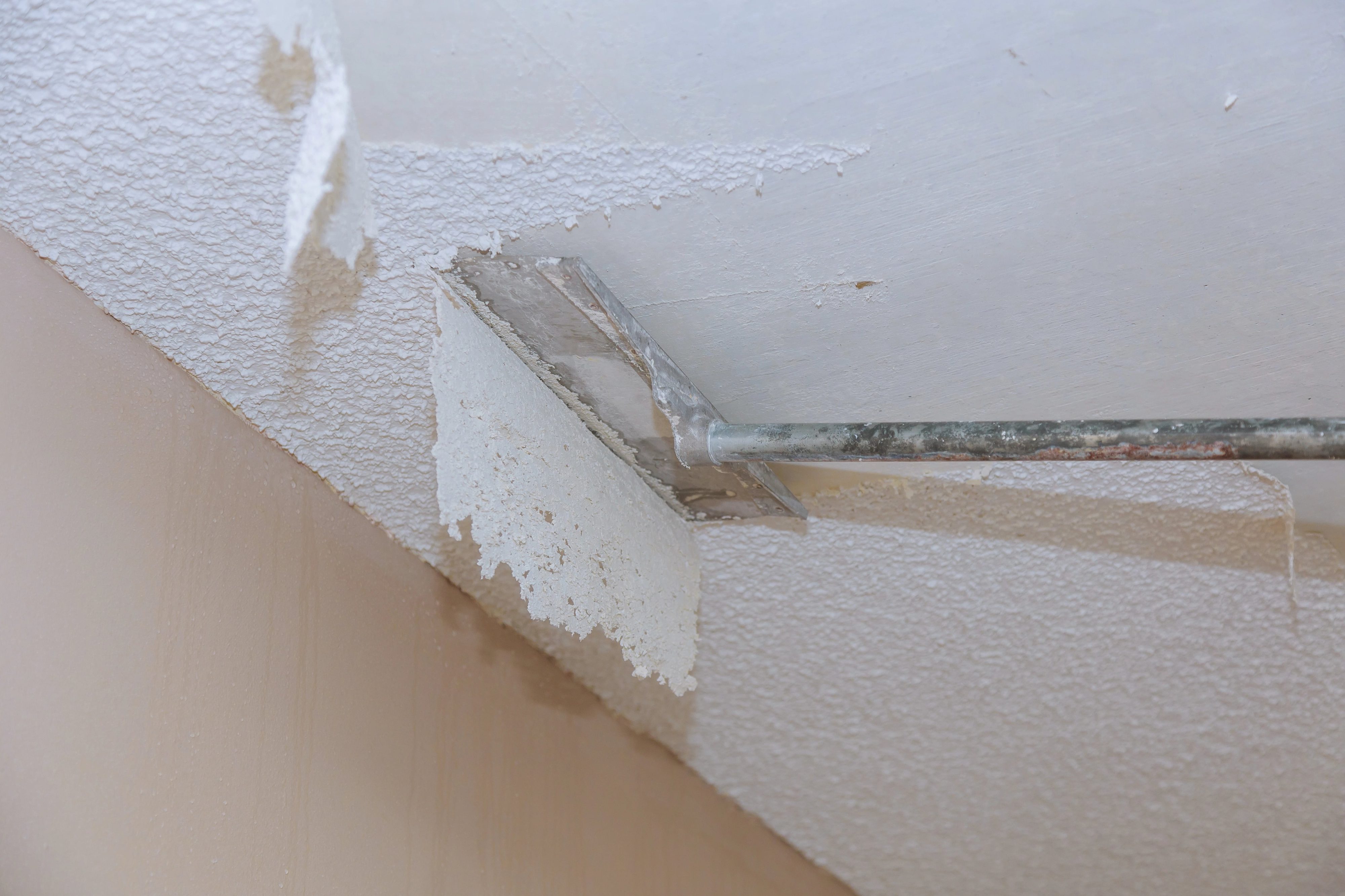 Everything You Need to Know About Popcorn Ceiling Removal 1 Scraping asbestos popcorn ceiling.